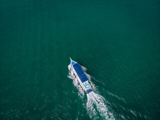 speed Boat/ cruise yacht with blue roof at sea leaving a wake, aerial view