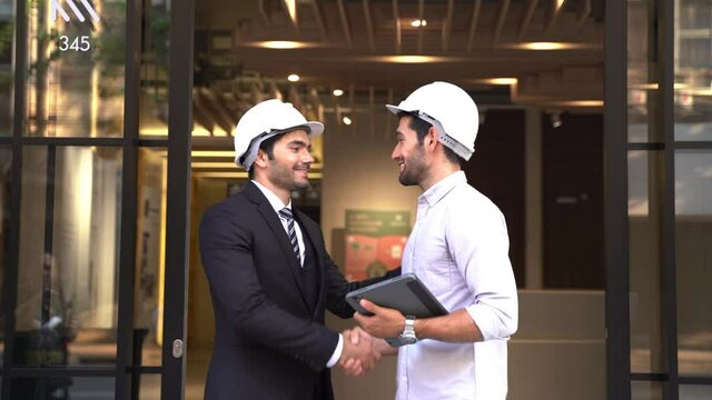 Group Of Business And Engineers Meeting And Shake Hand After Walking Through Automatic Sliding Door Out Of Office Building.