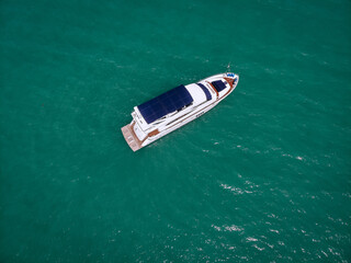 Fototapeta premium Aerial photo of an isolated luxury white yacht with blue roof design in the sea