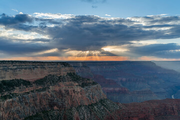 sunset shot of sunbeams extending down from behind clouds at hopi point of the grand canyon national park in arizona