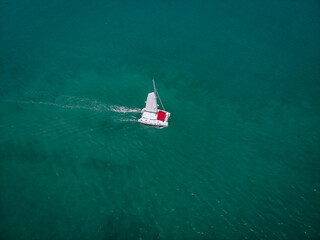 Sailing ship yachts with white sails and  red awning from the sun for passengers at open sea....