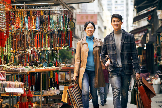 young asian couple walking on steps carrying shopping bags