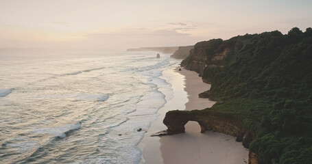Sunrise at ocean cliff shore with giant hole at rock wall aerial view. Tropical nature landscape of...