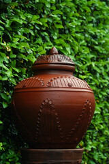 Brown ceramic barrel with a blurry green plant background