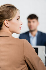 Back view of businesswoman looking away with blurred co-worker on background