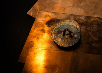 A bitcoin coin lying on a shiny copper plate.