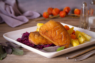 Roast duck breast fillets with potatoes, carrots, red cabbage and herbs. horizontal photo.