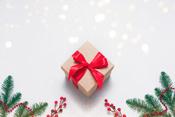 Vintage craft gift box with red ribbon as presenf for Christmas, New year on white background with fir tree branch, garland and lights. Flat lay