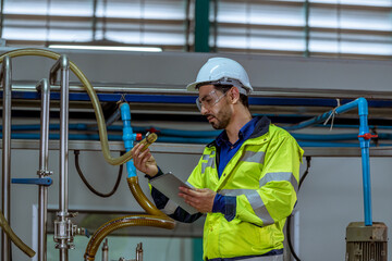 Engineer of bottle beverage factory wearing safety hat working check quality of machine to produce...