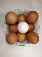 Close-up view of raw chicken eggs in bowl on white cloth background