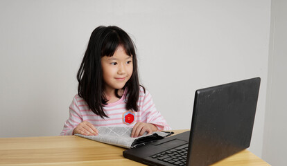 young girl with laptop in front and studying online through remote computer during home quarantine
