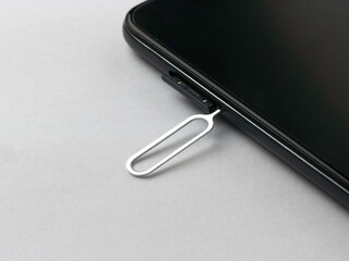 Sim card tray remover eject pin key tool and smartphone.