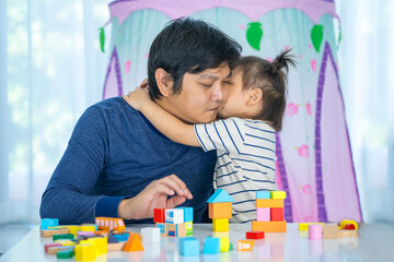 Obraz premium Happy kid, Little girl playing Developmental toy. little girl play brick toy and kiss her dad in home sweet home.