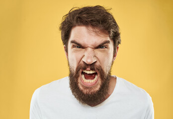 A man with a beard and mustache on a yellow background and a white T-shirt