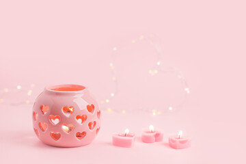 Decorative pink ceramic lanterns with heart cutouts lit by glowing candles onpink background, copy space, Saint Valentine, Mother day, Woman day concept, banner, flyer, greeting card, invitation