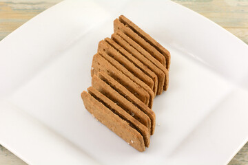 Stack of chocolate creme filled sandwich cookies on white snack plate