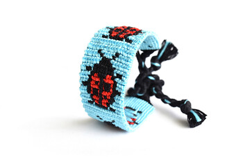 Selective focus of tied woven DIY friendship bracelet with alpha pattern Ladybug handmade of...