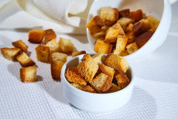 Square toasted pieces of homemade delicious rusk, hardtack, Dryasdust, zwieback in a plate on a white tablecloth.