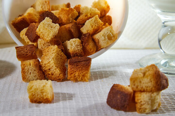 Square toasted pieces of homemade delicious rusk, hardtack, Dryasdust, zwieback in a plate on a white tablecloth.