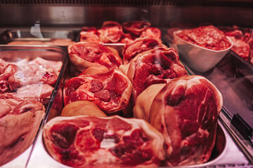 Obraz premium Different juicy and quality raw meat in refrigerator of modern meat shop. Close up of raw meat in counter.
