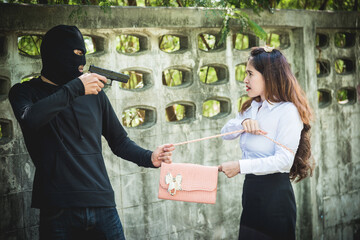 The robber is robbing the female with a gun, pointing the gun to the face