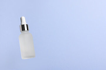 White translucent bottle with dropper with a beauty serum on a blue background. Glass packaging for cosmetic product, essential aroma oil. Skin care, hydration and nutrition with collagen. Levitation