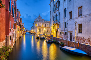 Fototapeta na wymiar Canal in the old town of Venice at dusk with the Scuola Grande di San Marco in the back