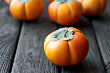 Ripe fresh persimmon on brown wooden rustic background. Close-up, selective focus