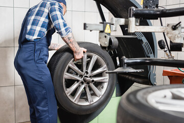 Fototapeta premium cropped of technician examining wheel on balance control machine in garage on blurred foreground