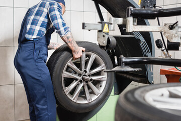 cropped of technician examining wheel on balance control machine in garage on blurred foreground