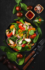 Fresh salad with spinach, chicken, tomatoes, arugula, corn lettuce and onion. Healthy food. Black table