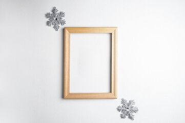 Mockup wooden frame and decorative snowflakes on a white background. An idea for your Christmas and holiday photos. Holiday text in a frame