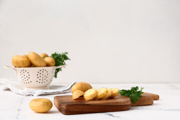 Cutting board with raw potatoes and parsley on table