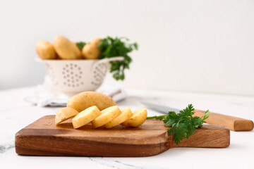 Cutting board with raw potatoes and parsley on table