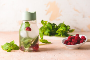 Bottle of mint infused water with raspberry on light table
