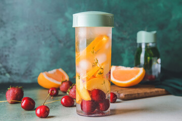 Bottle of herbal infused water with berries and citrus on table