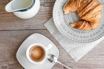 sunday morning breakfast top view with espresso coffee, milk and croissant on a wooden table