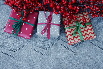 Different Christmas gift boxes on knitted gray wool background. Christmas festive background