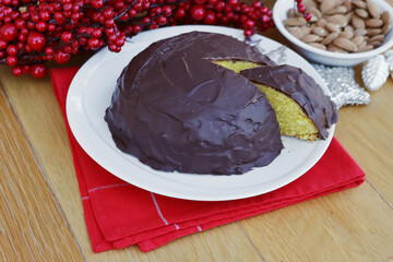 Italian traditional sweet cake called Parrozzo made with almonds on a plate on wooden table with Christmas decoration 