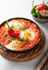 Shakshuka, fried eggs with vegetables in a frying pan, traditional israeli cuisine