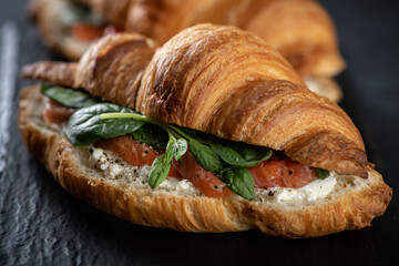 sandwich with salmon, spinach and cream cheese on black background, selective focus