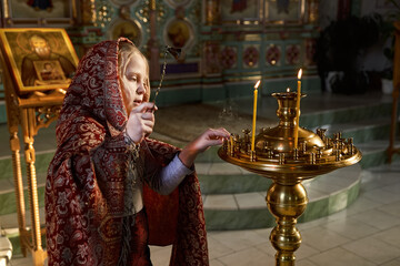 Religious girl with covered head praying in Christian Church