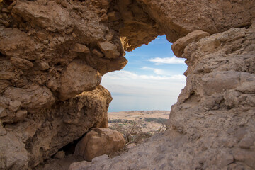 Hollow rock in Ein Gedi, in the background of the palm groves, the Dead Sea and Road No. 90. Israel.