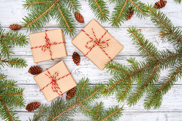 Fototapeta na wymiar Christmas gift boxes and fir branches with cones on wooden background