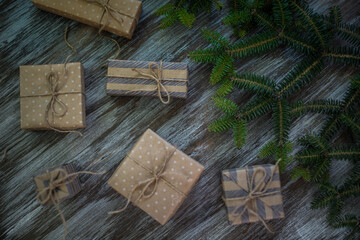 Christmas background. Gift boxes wrapped in craft paper, fir branches and garland lights.
