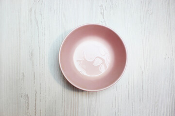 pink empty bowl, top view on white wooden background
