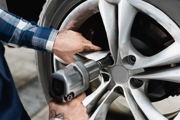 partial of technician fixing wheel on car with pneumatic wrench