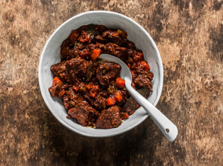 Slow cooker beer beef stew on a wooden background, top view. Delicious comfort homemade food