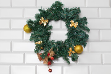 Naklejka premium Christmas holiday wreath with golden christmas balls and bows on white bricks wall