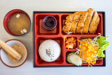 Top view of Japanese Bento Box with deep fried pork cutlet (tonkatsu set), salad and sauce. Seaweed...